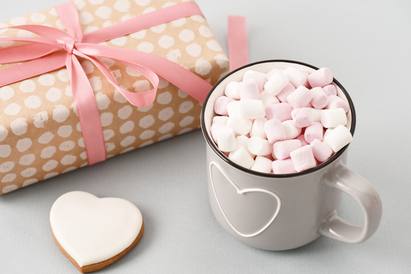Mug of Marshmallows Stands Next to Gift and Heart-Shaped Gingerbread